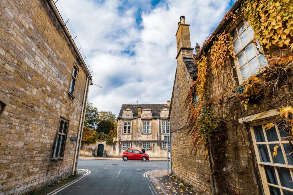 Explore the serene autumn charm of Burford's historic streets lined with ivy-covered stone houses.