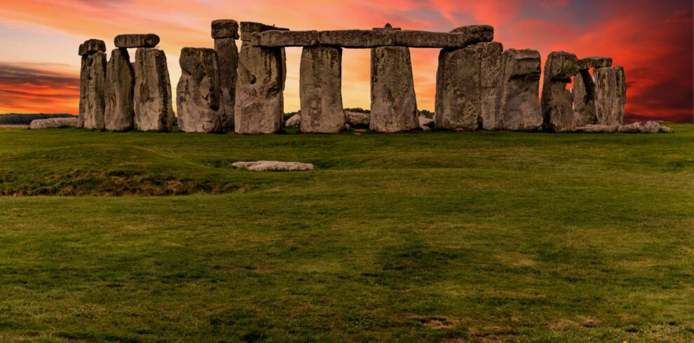 Capture of the iconic Stonehenge during a vibrant sunset with a dramatic sky.