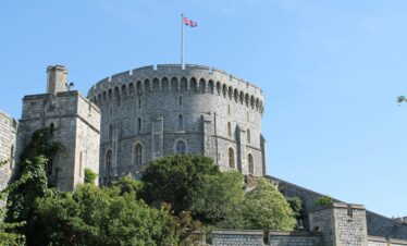Stone tower of Windsor Castle with Union Jack against a clear blue sky.