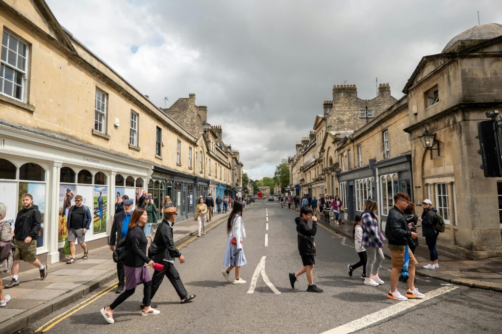People walking through a vibrant street in Bath, UK, showcasing Georgian architecture and lively urban life.
