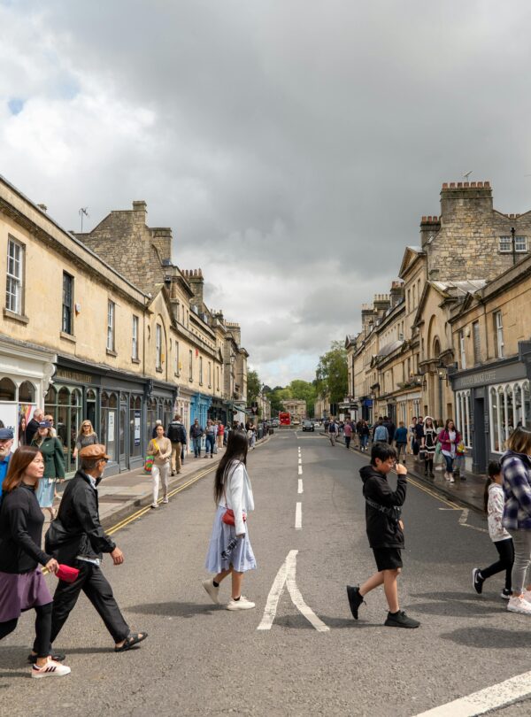 People walking through a vibrant street in Bath, UK, showcasing Georgian architecture and lively urban life.