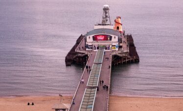 Scenic view of Bournemouth Pier with people against a tranquil sea at dusk.